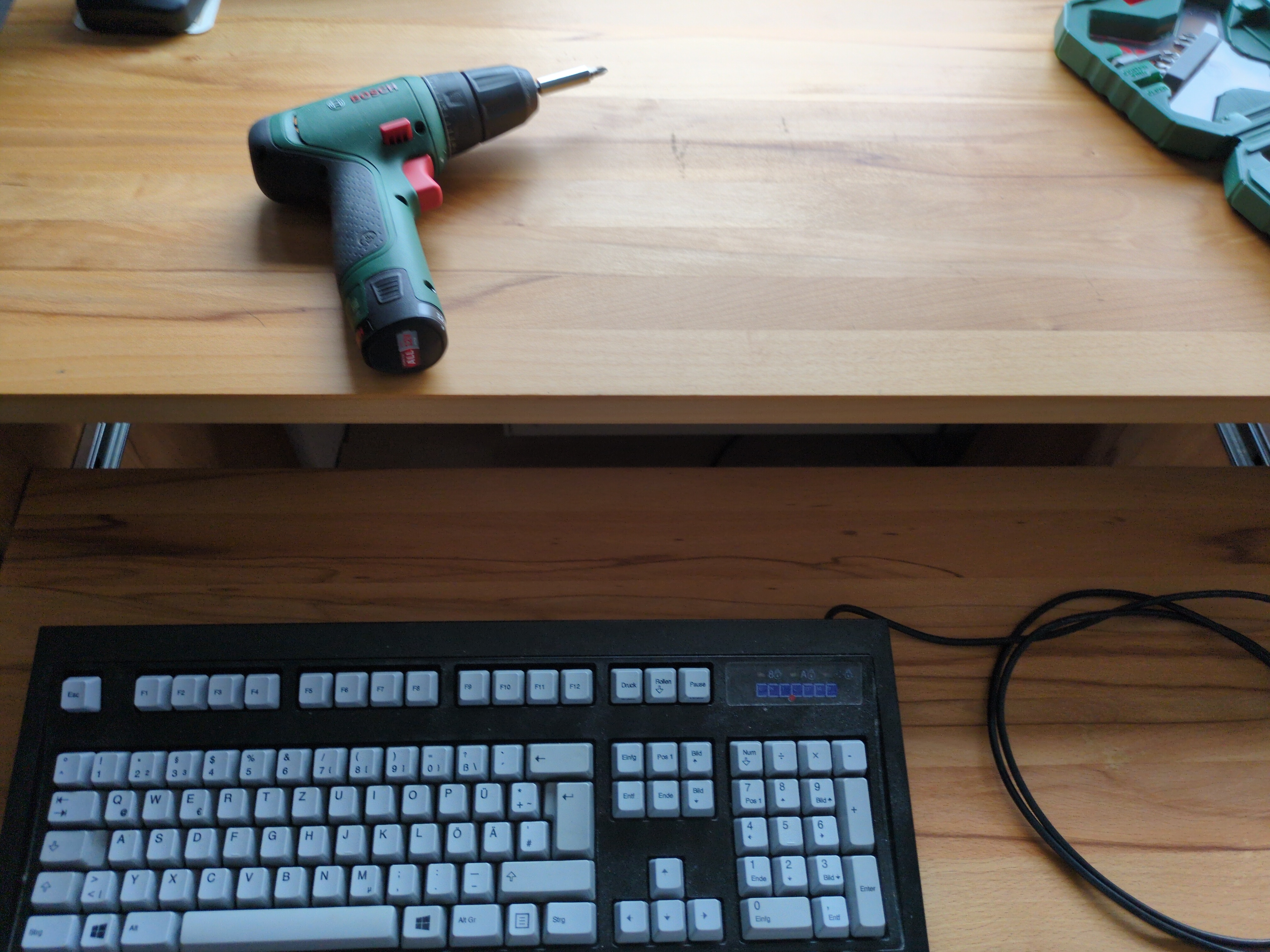 A picture of a desk with a keyboard and a electric drill on it