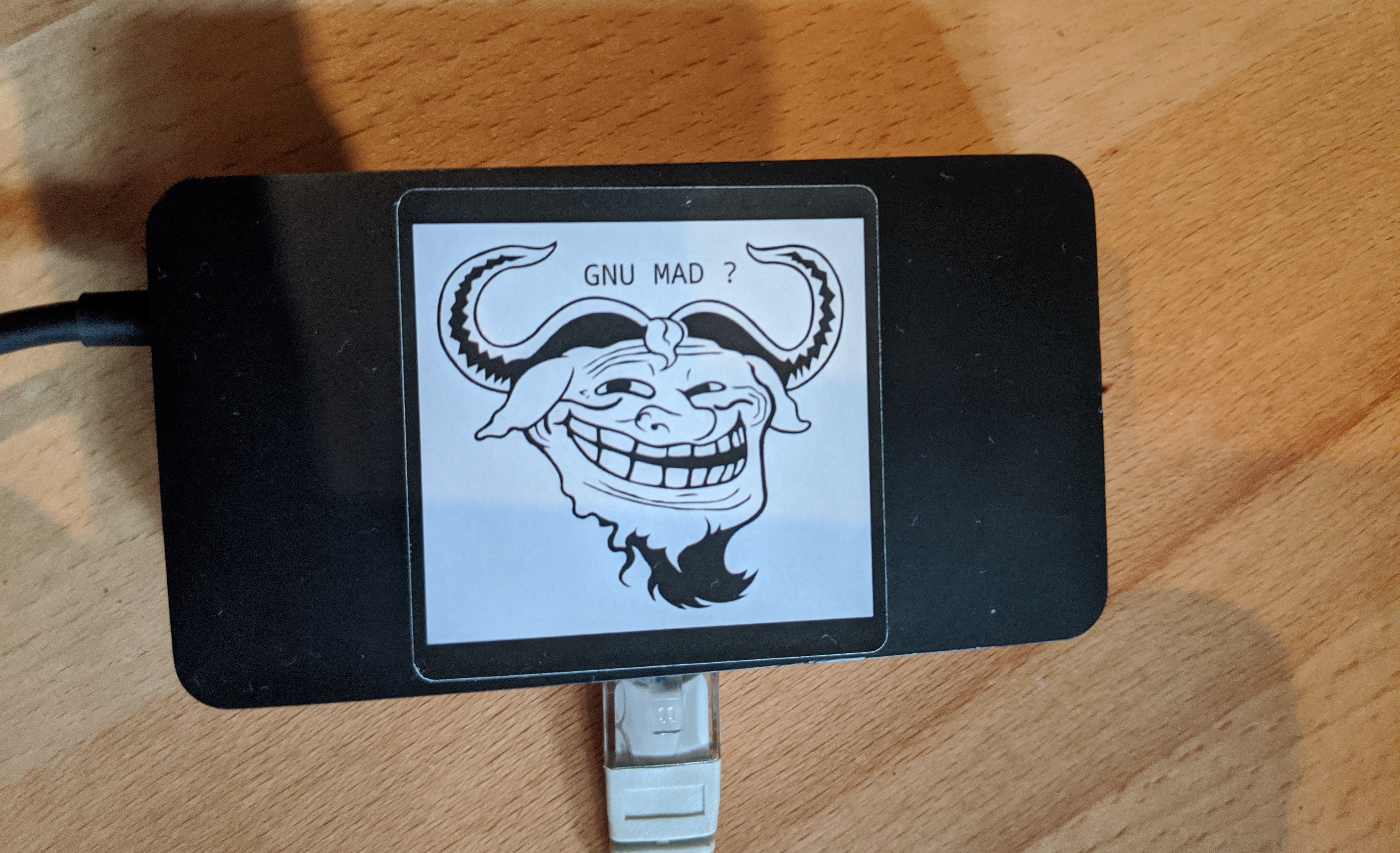 A dock with a sticker on top. The sticker is depicting the GNU logo morphed with the trollface, captioned "GNU MAD?"