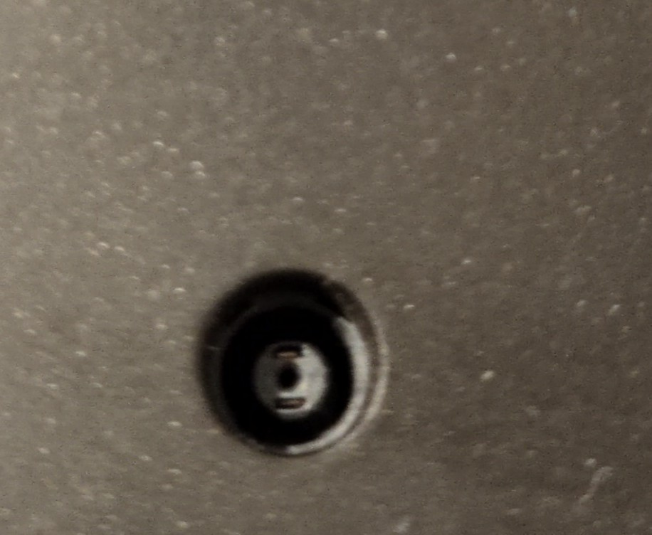 A closeup of a connector. It's a barrel jack socket, with one big hole in the middle, and two smaller slits 