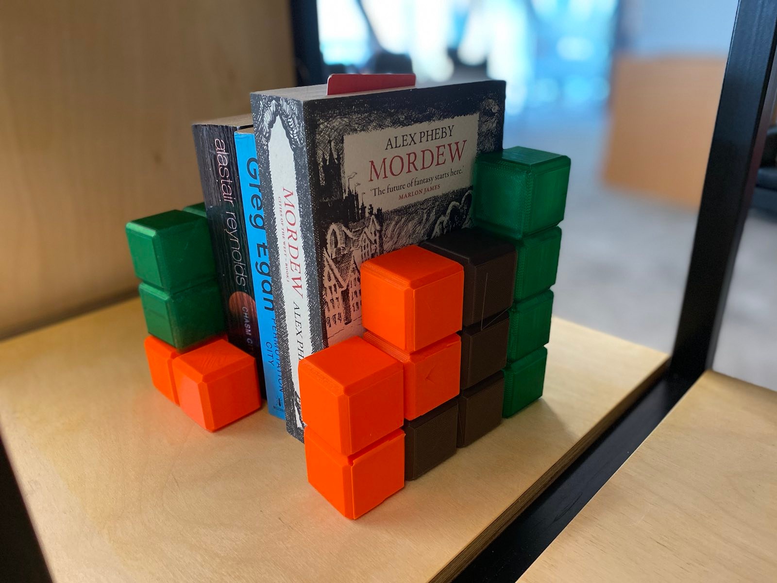 photo of tetromino bookends in 3 colours, bracketing some novels