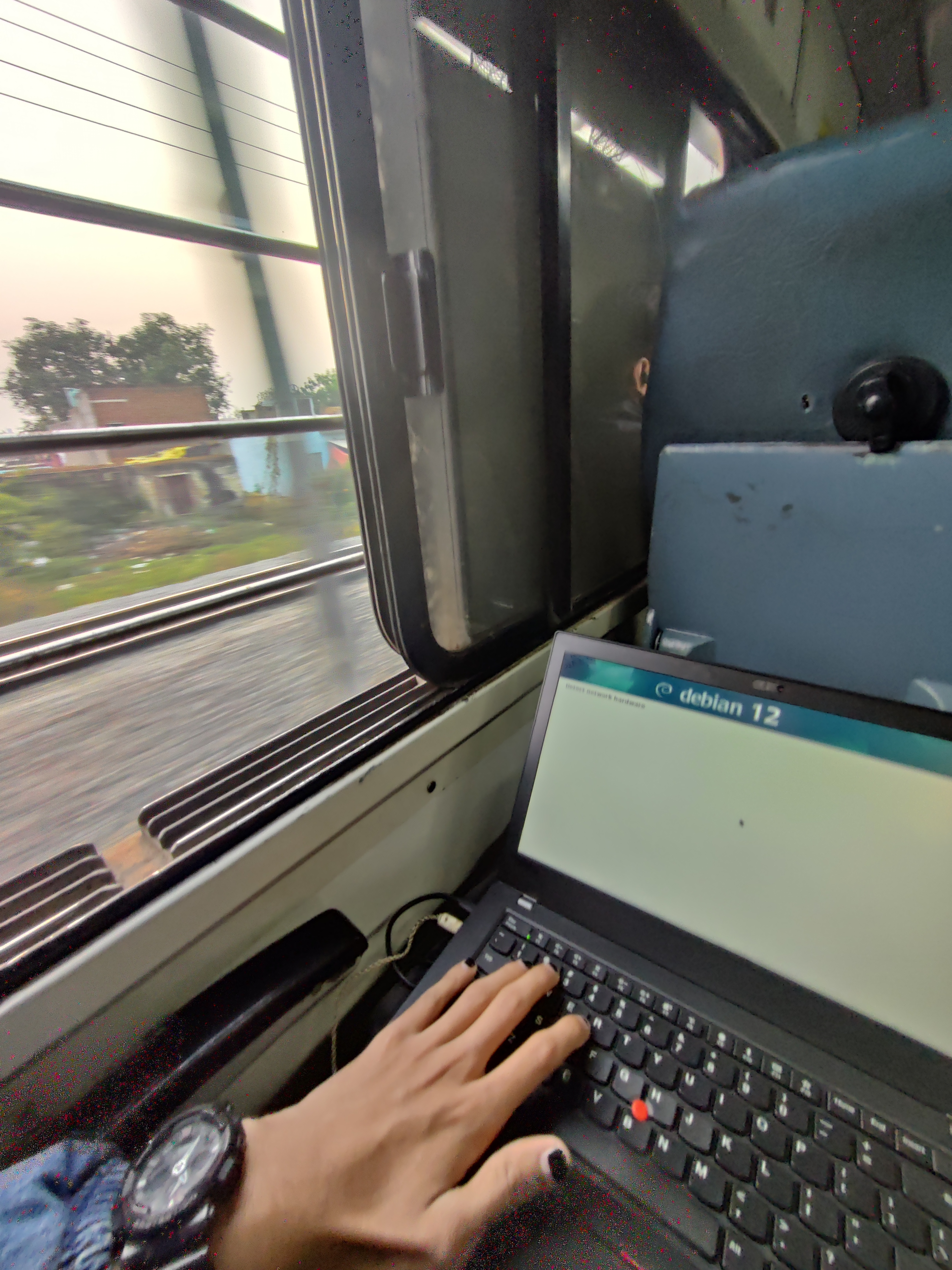 Debian Installer running on a T480 besides an open window on a Train