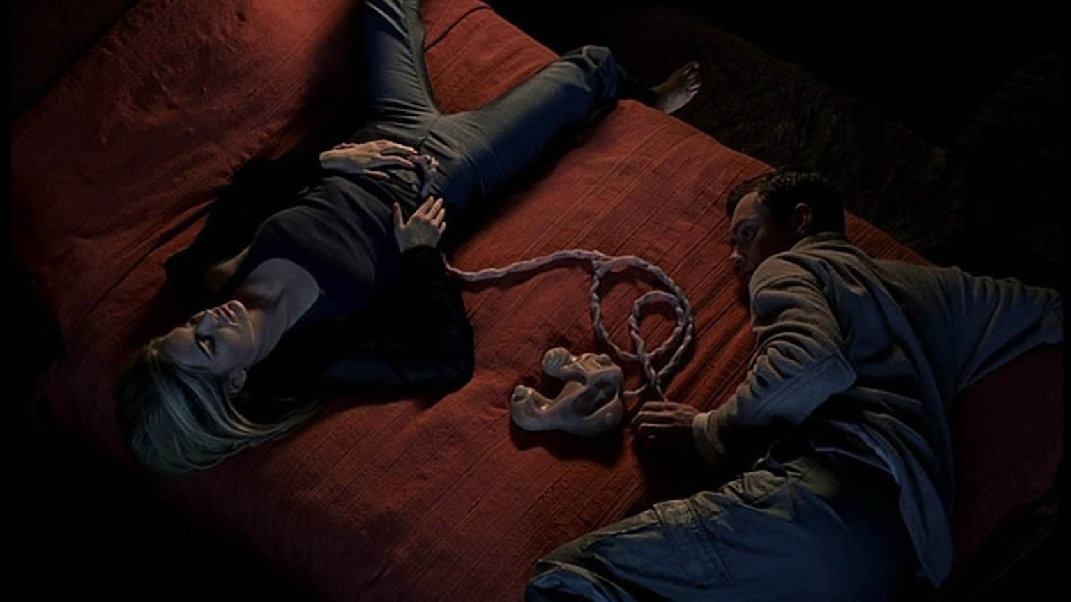 Still from the movie ExistenZ, with the protagonists prone on a bed plugged into the bio mechanical game 