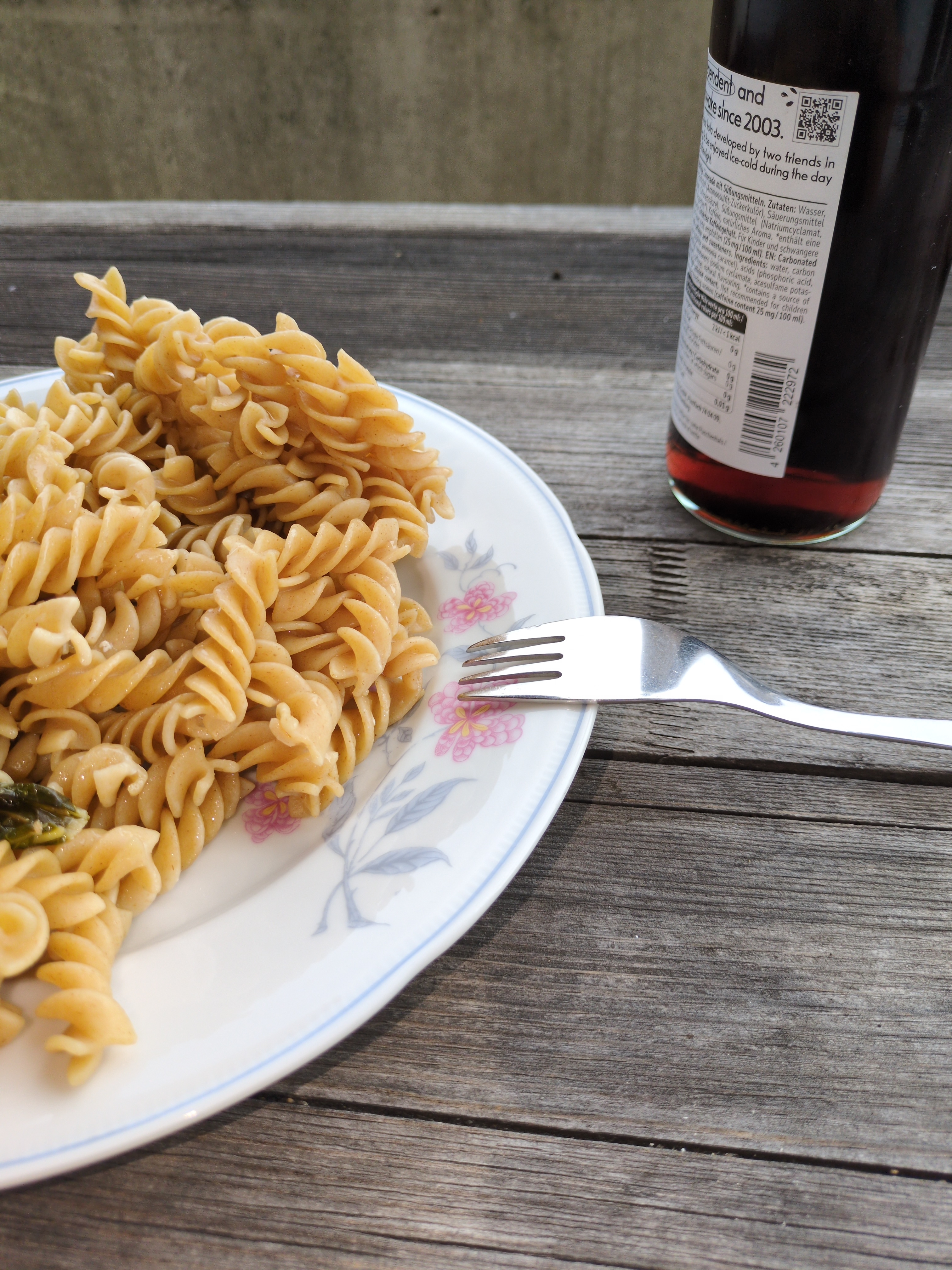 A plate with noodles, and a FritzKola beside it