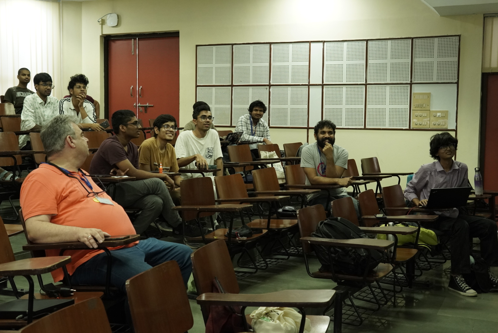 A classroom setting with bunch of people looking towards other side