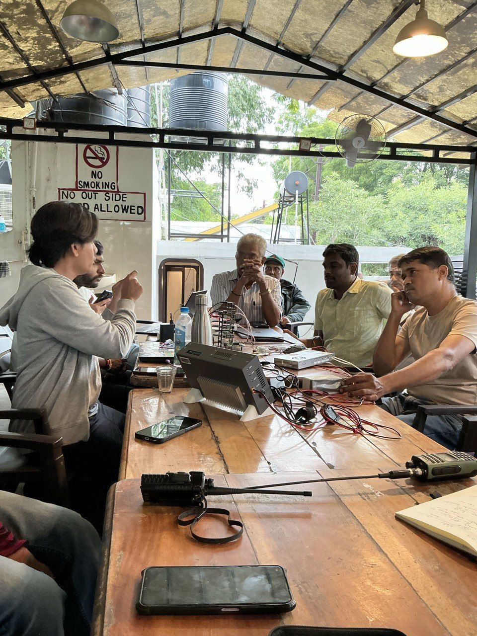 Group of people sitting around a talk and talking. One person is speaking and others are listening. 