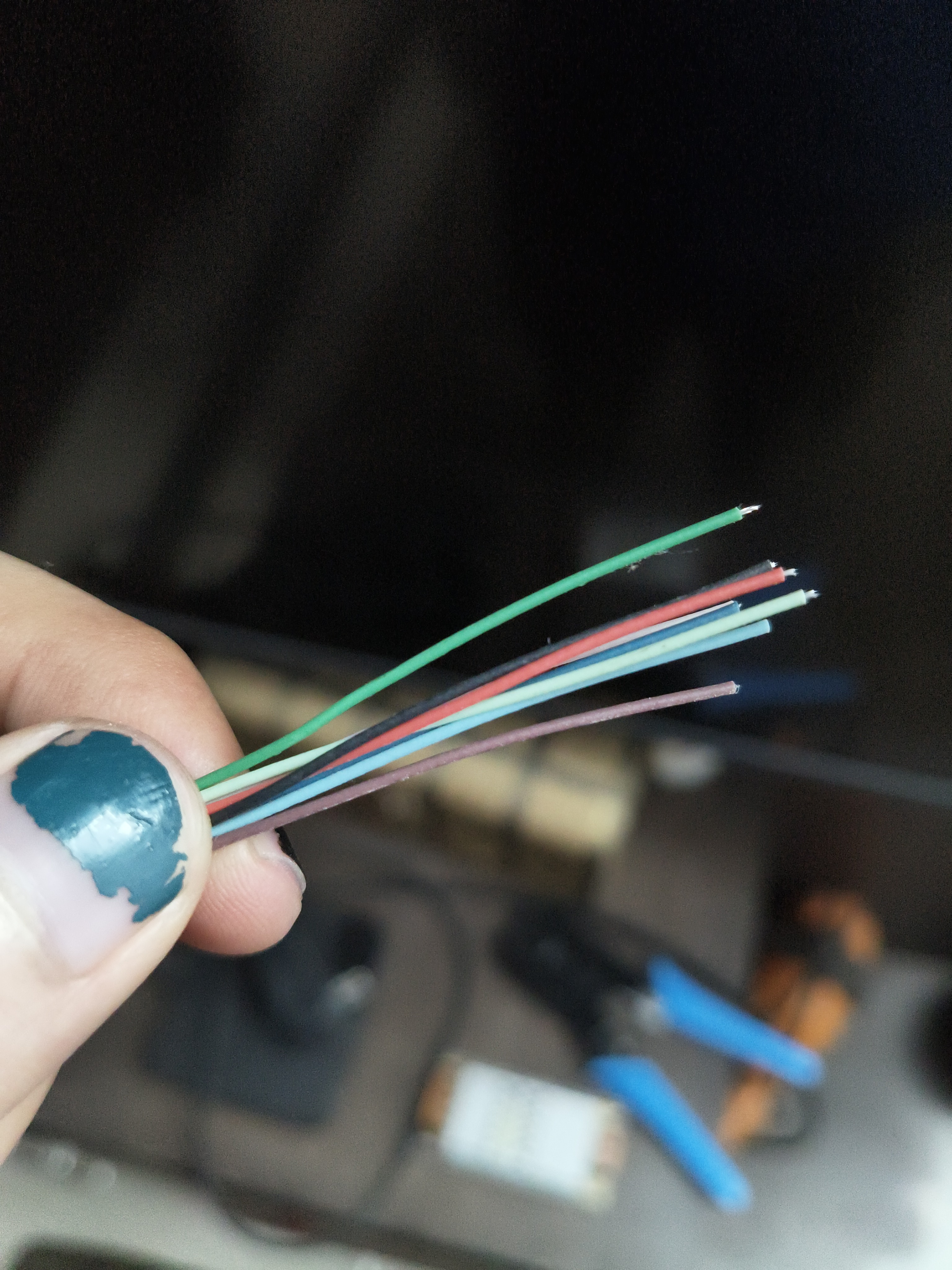 Stripped end of one of the cable, 8 cables with non standard coloured jackets spill out with some exposing a decidedly non copper looking core! my cheap ethernet crimper in the background too :)